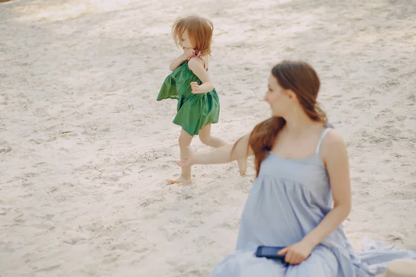 stock image A beautiful young mother plays on the beach with her little daughter