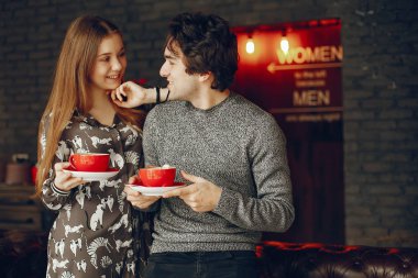 Güzel çift ayakta bir kafede. Sevimli kız bir gömlek. Gri süveterli adam. Bir kahve içme çift