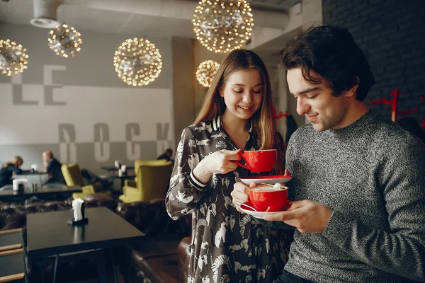 Güzel çift ayakta bir kafede. Sevimli kız bir gömlek. Gri süveterli adam. Bir kahve içme çift