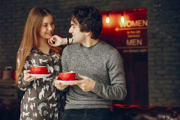 Güzel çift ayakta bir kafede. Sevimli kız bir gömlek. Gri süveterli adam. Bir kahve içme çift