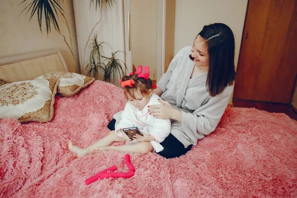 Mãe com filha sentada em uma cama — Fotografia de Stock