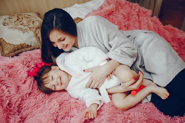 Mãe com filha sentada em uma cama — Fotografia de Stock