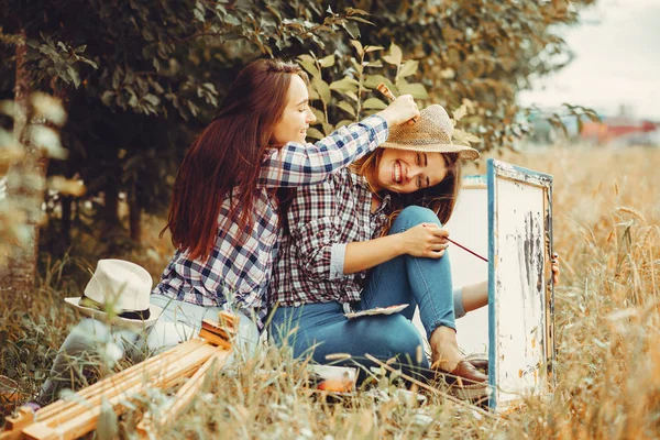 Two beautiful girls drawing in a field — Stock Photo, Image