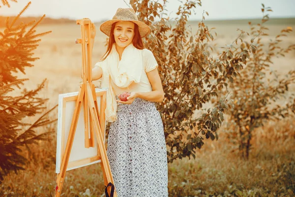 Beautiful girl drawing in a field