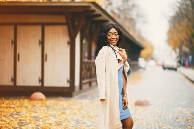 Bir sonbahar şehrinde yürüyen siyah kadın