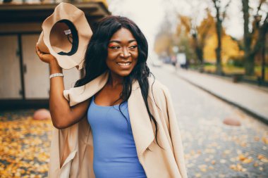 Bir sonbahar şehrinde yürüyen siyah kadın