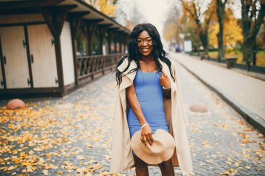 Bir sonbahar şehrinde yürüyen siyah kadın