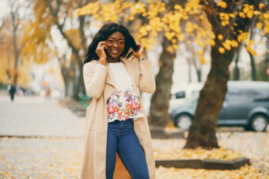 Bir sonbahar şehrinde duran siyah kadın