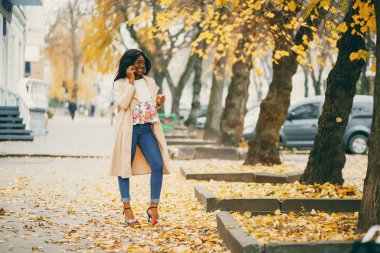 Bir sonbahar şehrinde duran siyah kadın