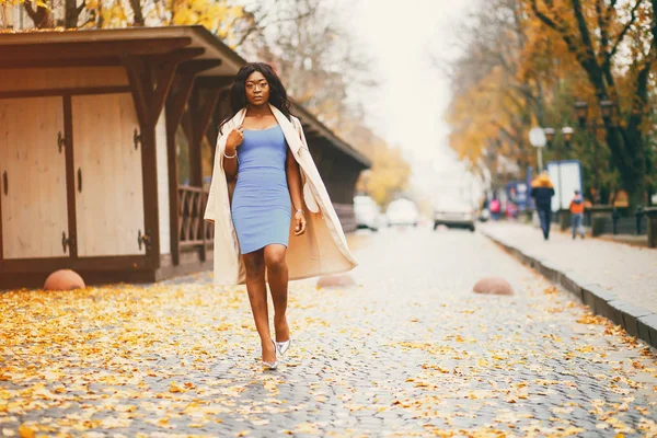 Bir sonbahar şehrinde yürüyen siyah kadın