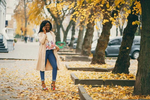 Чорна жінка стоїть в осінньому місті — стокове фото