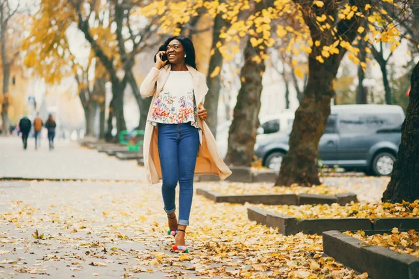 Черная женщина стоит в осеннем городе — стоковое фото