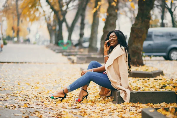 Mulher negra sentada em uma cidade de outono — Fotografia de Stock