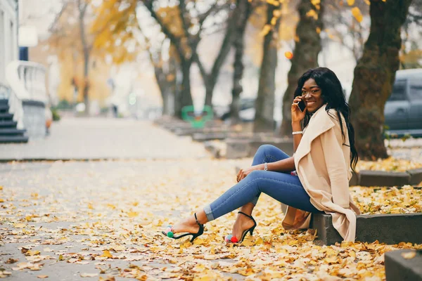 Mulher negra sentada em uma cidade de outono — Fotografia de Stock