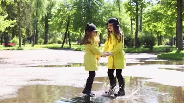 Niñas corriendo a través de los charcos en el parque — Vídeo de stock