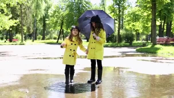 Niñas corriendo a través de los charcos en el parque — Vídeos de Stock