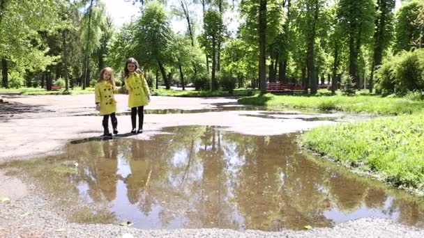 Jeunes filles courant à travers les flaques d'eau dans le parc — Video