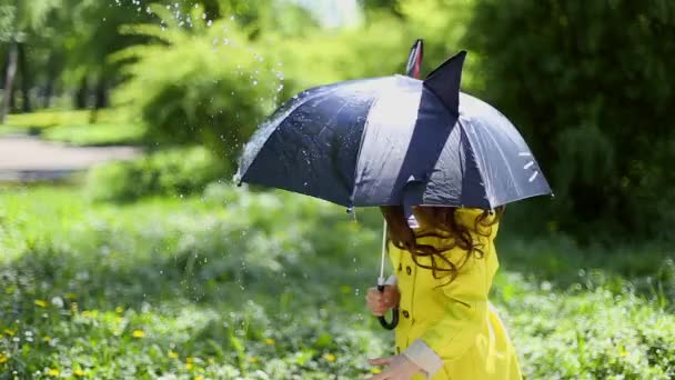 Jovencita sosteniendo un paraguas y jugando bajo la lluvia — Vídeo de stock