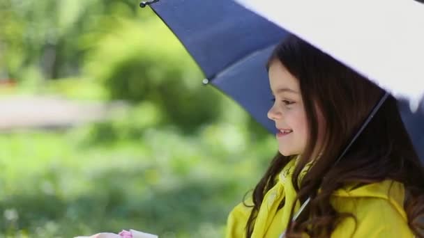 Junges Mädchen hält einen Regenschirm und spielt im Regen — Stockvideo