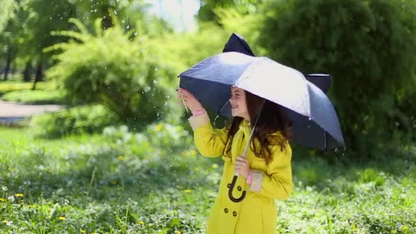 Junges Mädchen hält einen Regenschirm und spielt im Regen — Stockvideo