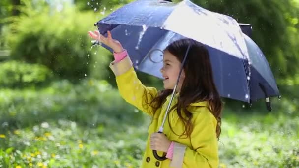 Молодая девушка держит зонтик и играет под дождем — стоковое видео