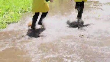 Parkta su birikintilerinde oynayan ve koşan iki kız