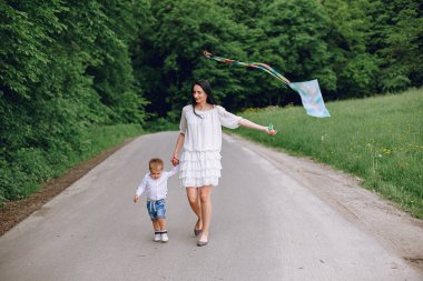 Anne ve oğlu yaz parkında oynuyorlar.