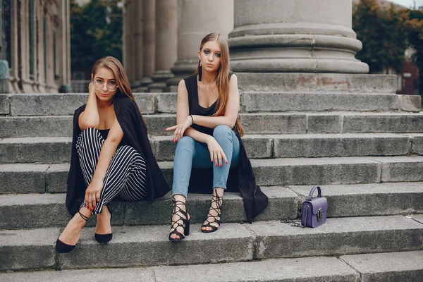 Mode meisjes zitten in een zomerstad — Stockfoto