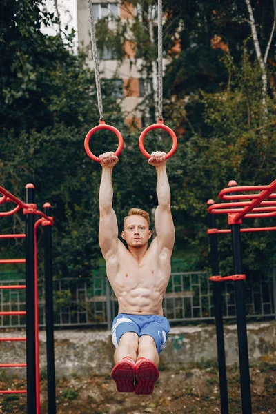 Bonito homem treinando em um parque de verão — Fotografia de Stock