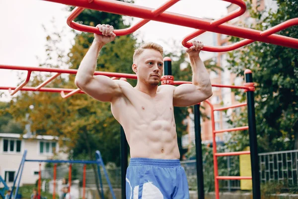 Bonito homem treinando em um parque de verão — Fotografia de Stock