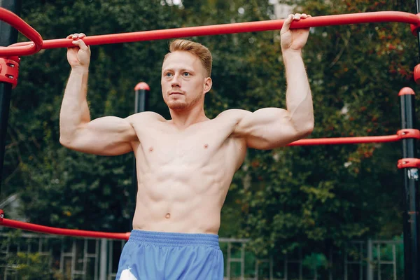 Bonito homem treinando em um parque de verão — Fotografia de Stock