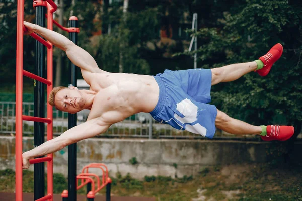 Bonito homem treinando em um parque de verão — Fotografia de Stock