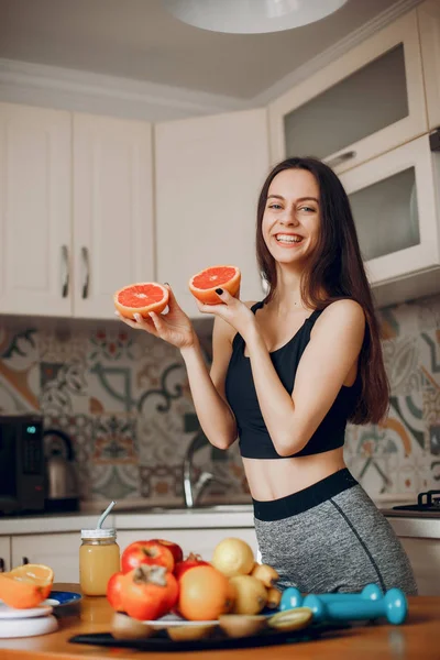 Sports girl in a kitchen with fruits