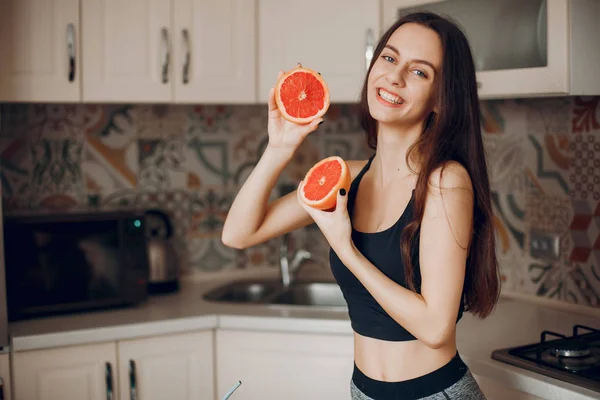 Menina de esportes em uma cozinha com frutas — Fotografia de Stock