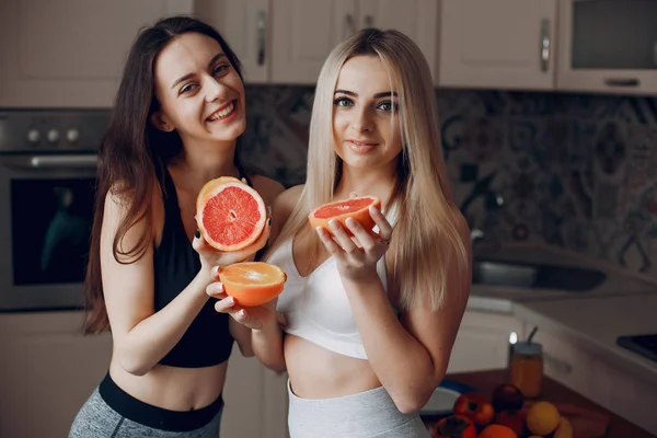 Sports girlss in a kitchen with fruits — Stock Photo, Image