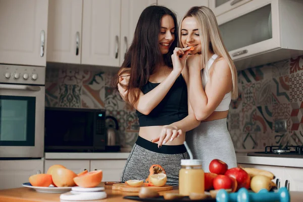 Sports girlss in a kitchen with fruits