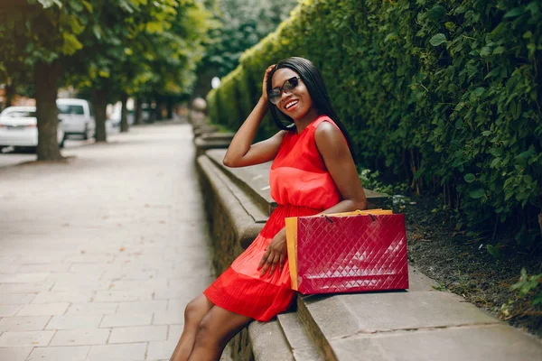 Menina preta bonita com sacos de compras em uma cidade — Fotografia de Stock