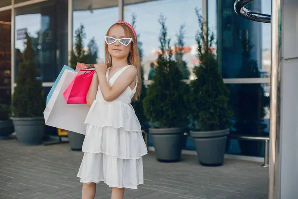 Schattig klein meisje met boodschappentas in een stad — Stockfoto