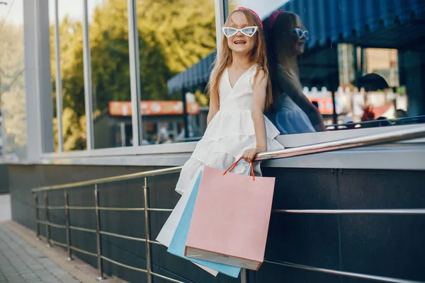 Roztomilá holčička s nákupními pytli ve městě — Stock fotografie