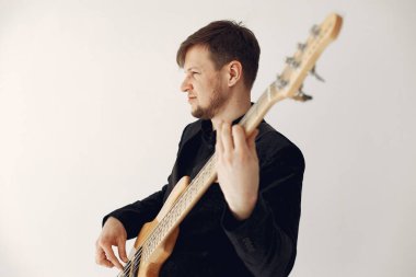 Siyah takım elbiseli adam gitarlı.