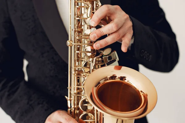 Man in black suit standing with a saxophone