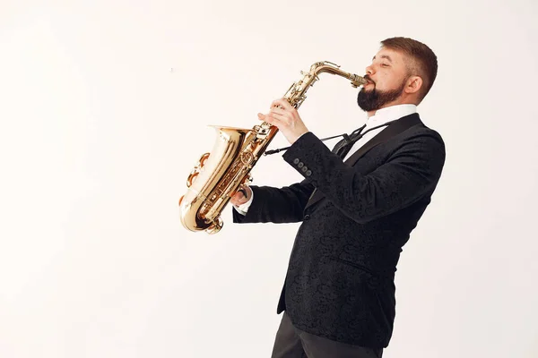 Man in zwart pak staand met een saxofoon — Stockfoto