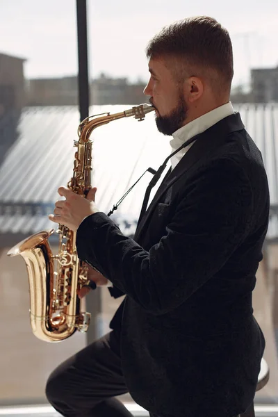 Man in zwart pak staand met een saxofoon — Stockfoto