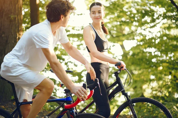 Sports couple riding bikes in summer forest