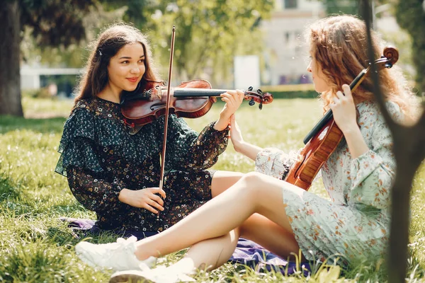 Belle e romantiche ragazze in un parco con un violino — Foto Stock