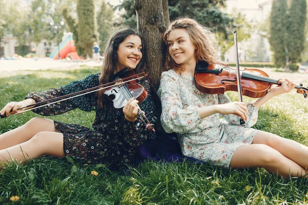 Gyönyörű és romantikus lányok egy parkban egy hegedűvel — Stock Fotó