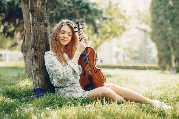 Menina bonita em um parque de verão com um violino — Fotografia de Stock