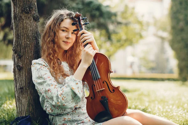 Menina bonita em um parque de verão com um violino — Fotografia de Stock