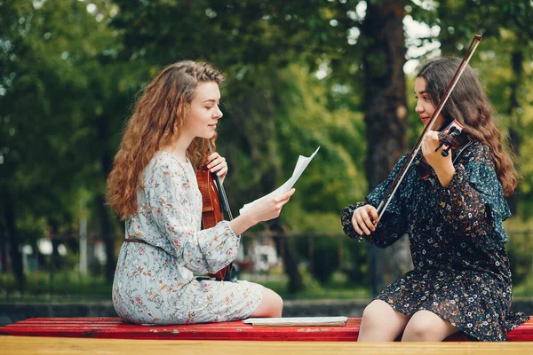 Meninas bonitas e românticas em um parque com um violino — Fotografia de Stock