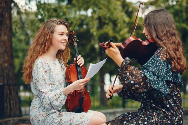 Gyönyörű és romantikus lányok egy parkban egy hegedűvel — Stock Fotó